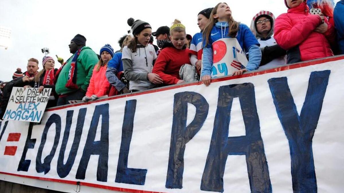 FILE - In this April 6, 2016, file photo, fans stand behind a large sign for equal pay for the women's soccer team during an international friendly soccer match between the United States and Colombia at Pratt & Whitney Stadium at Rentschler Field in East Hartford, Conn. The World Economic Forum's annual Global Gender Gap Report released on Oct. 25, 2016, found that the global gender pay gap will not be closed for another 170 years if current trends continue.