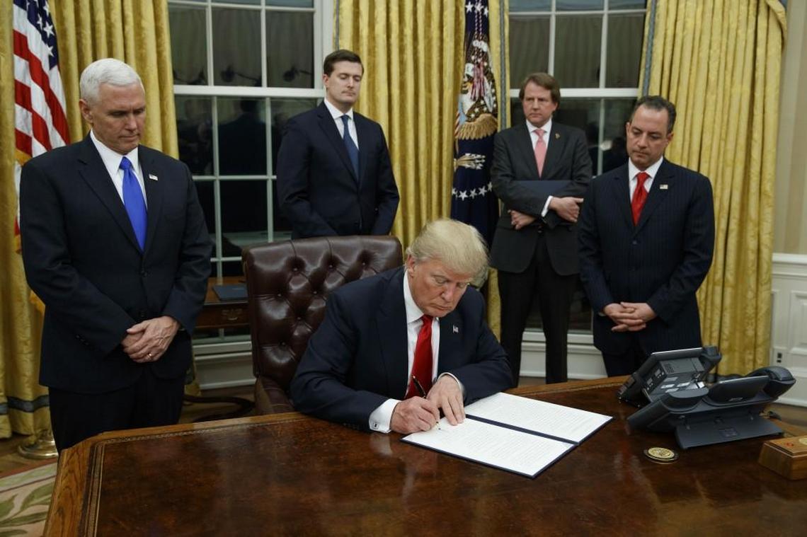 President Donald Trump, flanked by Vice President Mike Pence and Chief of Staff Reince Priebus, signs his first executive order on health care in January.
