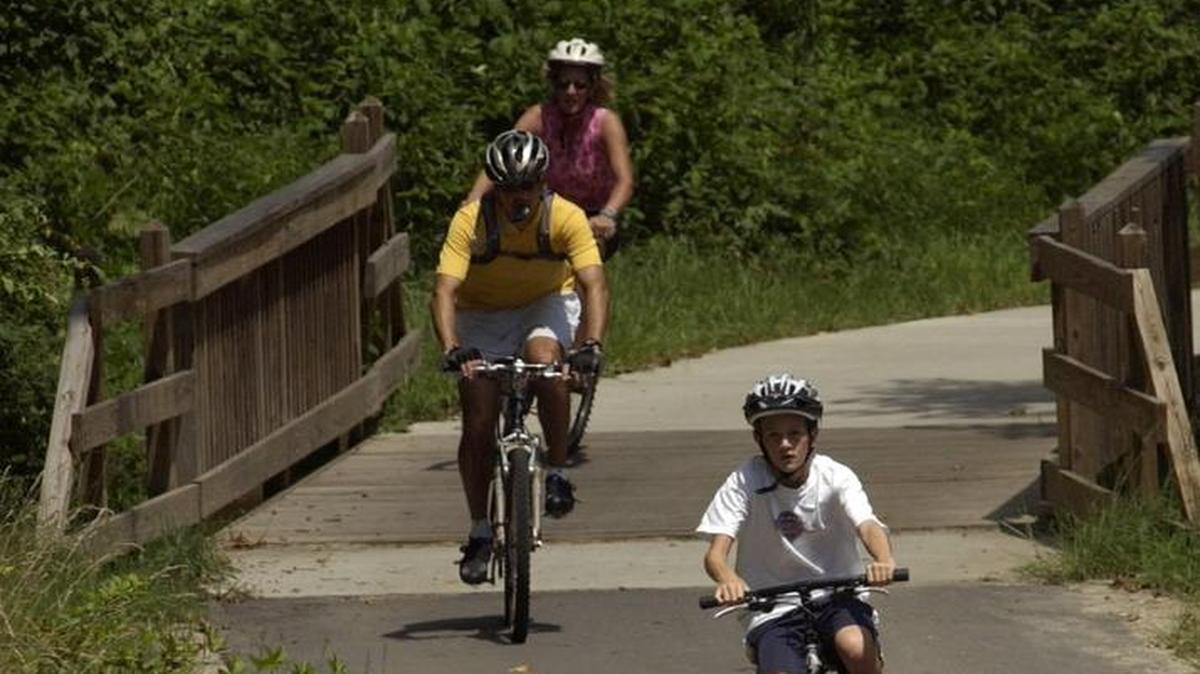 Bicyclists make their way along the greenway trail heading towards the NC Museum of Art from the pedestrian bridge over the Beltline. This trail goes past the NC Museum of Art and on through Umstead State Park.