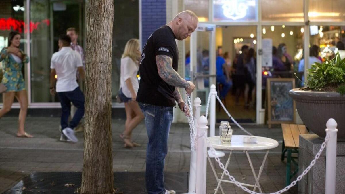 The Anchor Bar bouncer Adam Young closes the sidewalk patio in Raleigh just before 1 a.m.