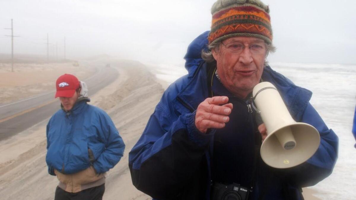 Trying to be heard above the storm on a narrow dune built to protect N.C. 12, coastal geologist Stan Riggs talks about erosion and sea-level rise in 2014.