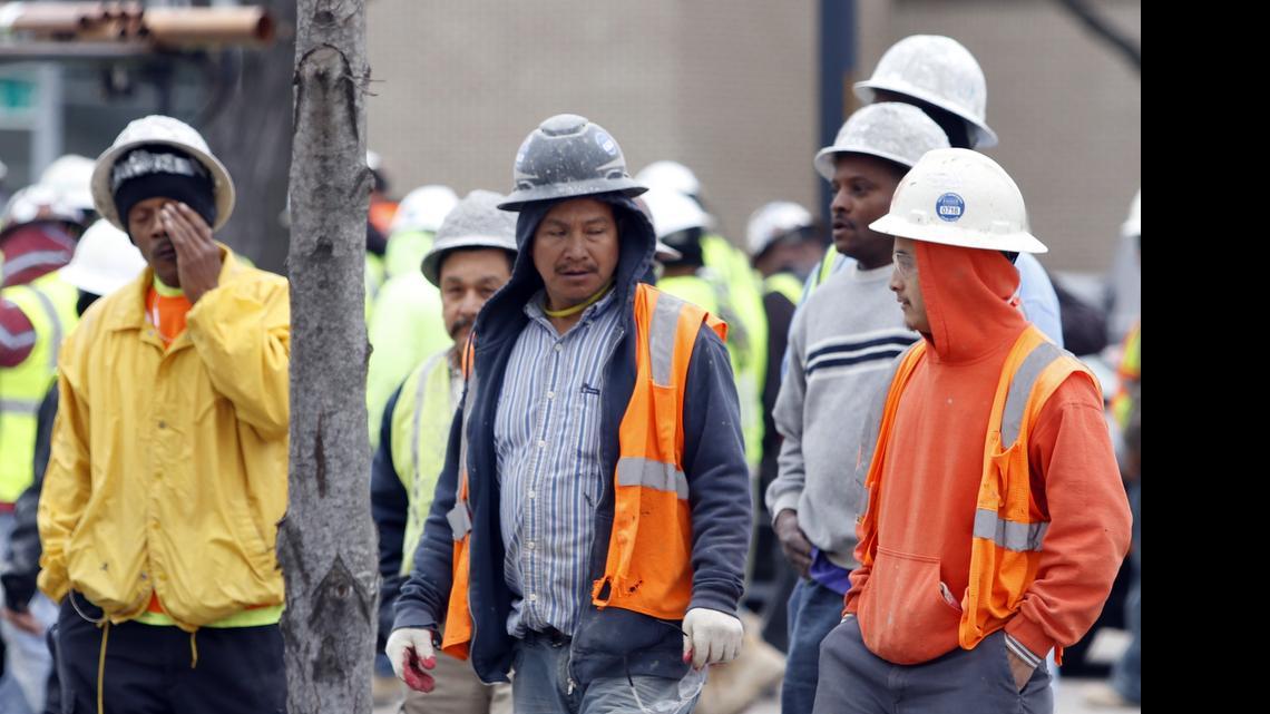 Stunned workers leave the scene of a construction accident that killed at least three workers in downtown Raleigh in March.
