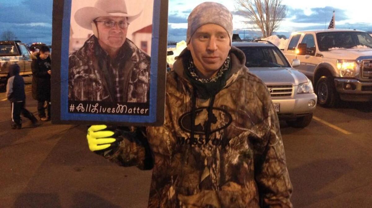 Tony Atencio of Burns, Oregon, holds a photo of rancher Robert LaVoy Finicum at a rally against Finicum’s slaying by law enforcement officers, and the presence of numerous heavily armed law enforcement officers at the standoff in Burns, Oregon.
