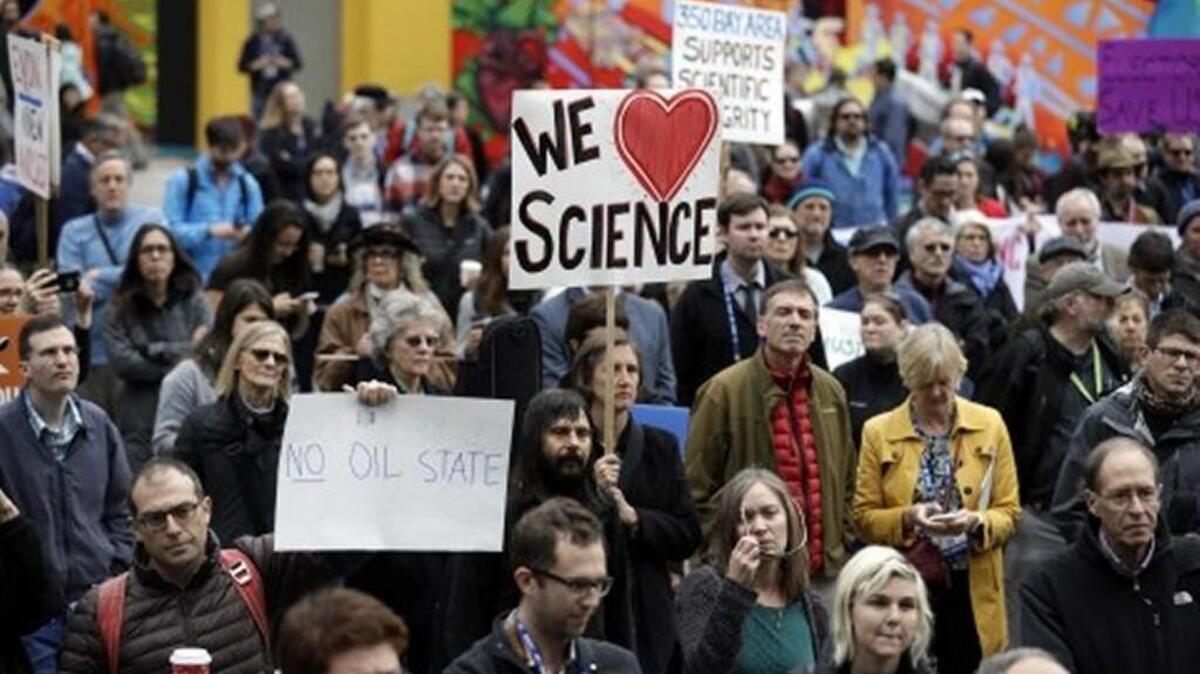 People hold signs as they listen to a group of scientists speak during a rally in conjunction with the American Geophysical Union’s fall meeting in San Francisco in January.