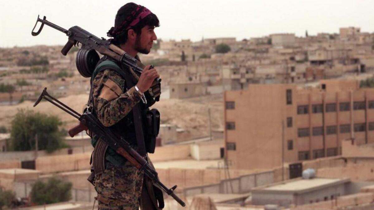 This April 30, 2017 photo provided by the Syria Democratic Forces (SDF), shows a fighter from the SDF carrying weapons as he looks toward the northern town of Tabqa, Syria.