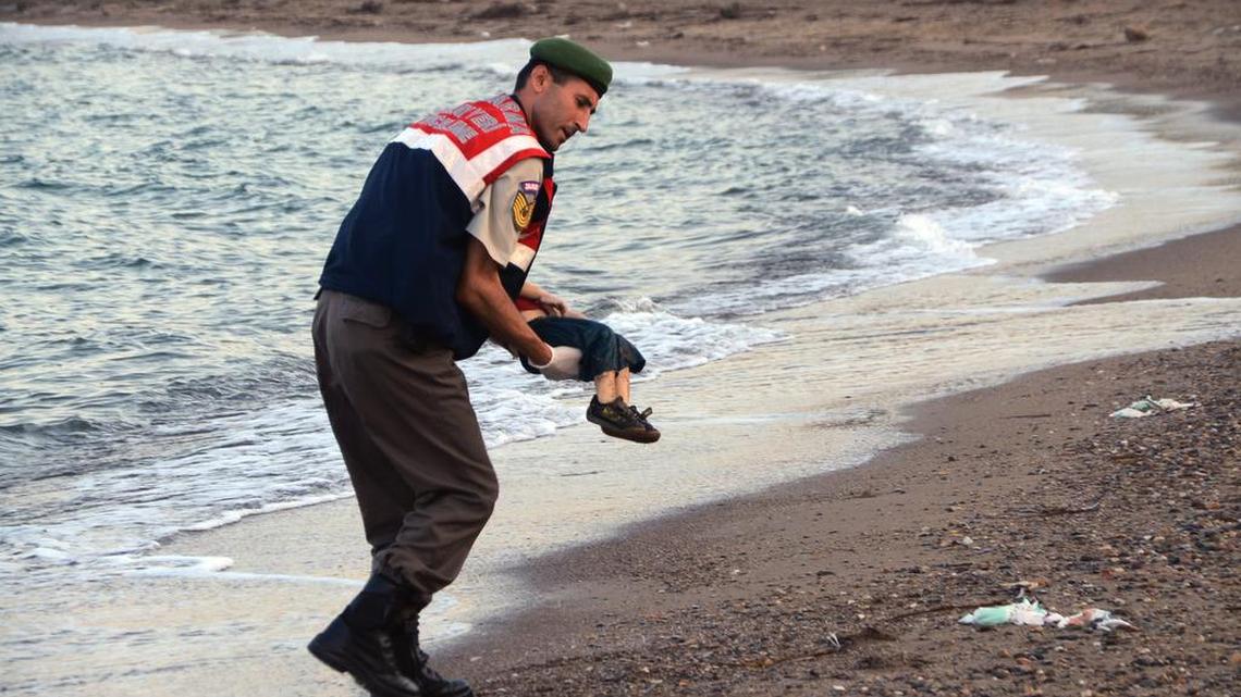 A paramilitary police officer carries the body of Aylan Kurdi, 3, after a number of migrants died when boats carrying them capsized.