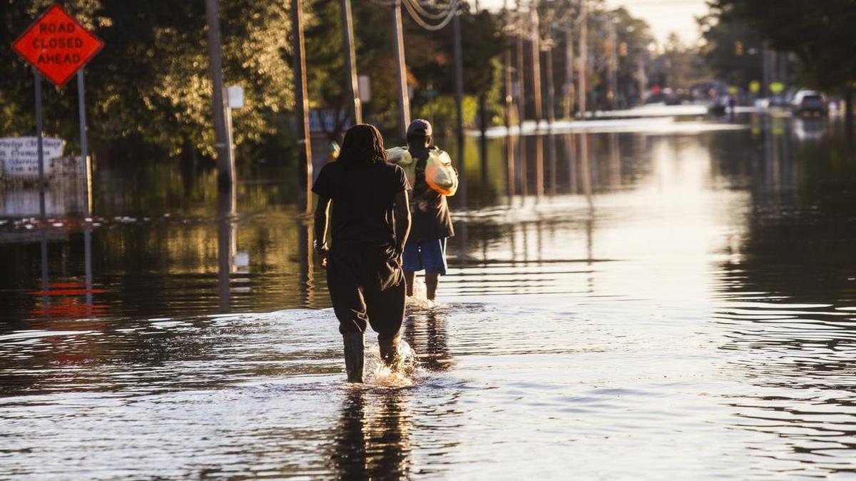 Residents walk down flooded streets after Hurricane Matthew caused downed trees, power outages, a municipal water outage and widespread flooding along the Lumber River in Lumberton.