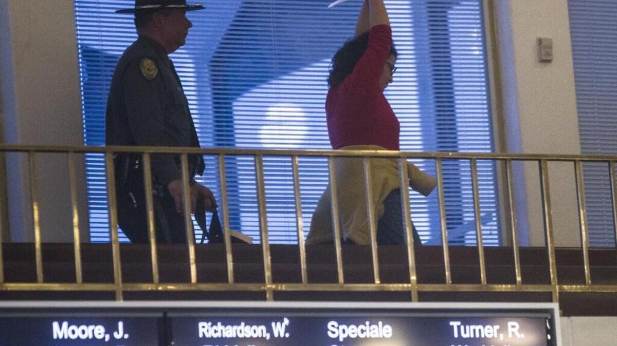 A protester is removed from the House gallery of the Legislature Building by a General Assembly police officer as legislators continued a special session Thursday, Dec. 15.