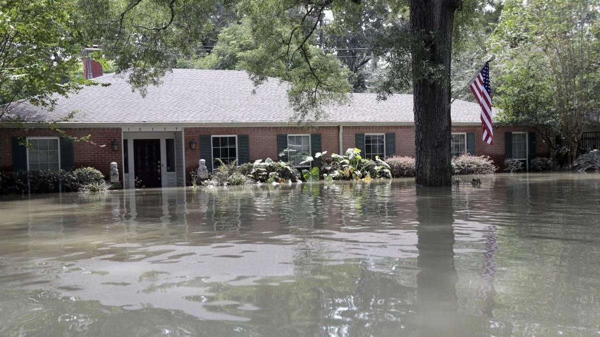 A United States flag hangs outside a flooded home in the aftermath of Hurricane Harvey, Monday, Sept. 4, 2017, near the Addicks and Barker Reservoirs in Houston.