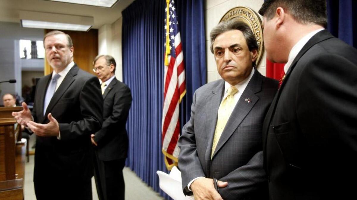 As Senator Phil Berger (Rep), left, addresses members of the media, Republican Senators Bob Rucho, second from right, and Andrew Brock, far right, briefly huddle during their press conference to discuss their ideas to put forth a new tax plan for North Carolina in 2013. The plan included revenue triggers that have automatically reduced the corporate tax rate in 2016 and 2017 despite tight state funding.