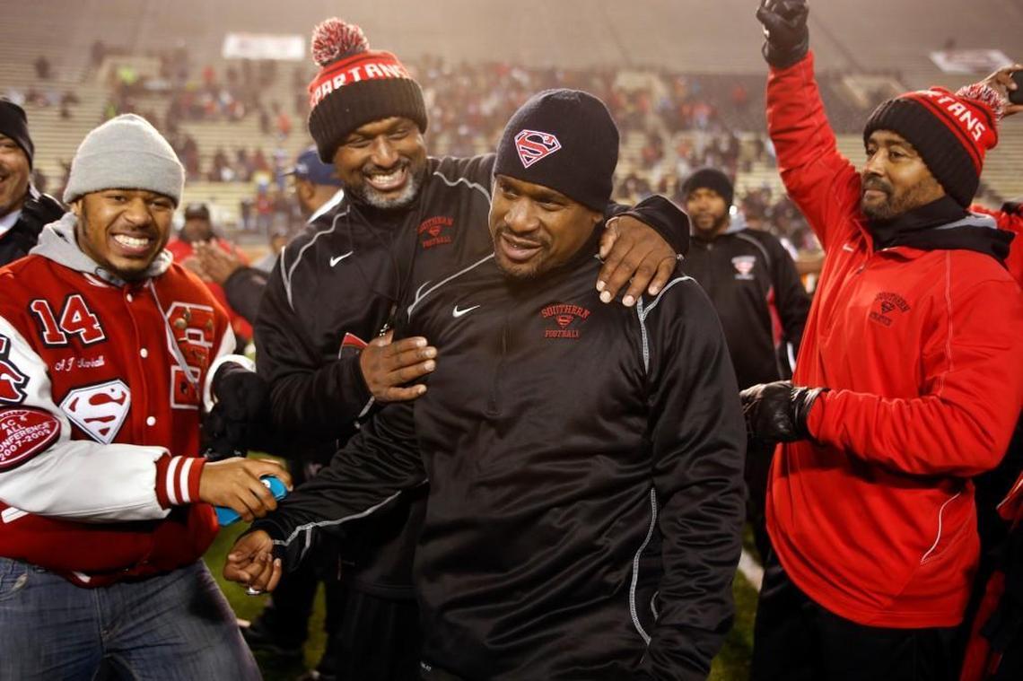 Southern Durham head coach Adrian Jones receives congratulations from his assistant coaches as he steps forward to accept the state championship plaque in 2013.