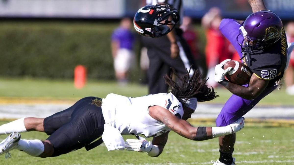 East Carolina Chris Hairston (22) is tripped up by Cincinnati's Leviticus Payne (9) during the game at Dowdy-Ficklen Stadium in Greenville.