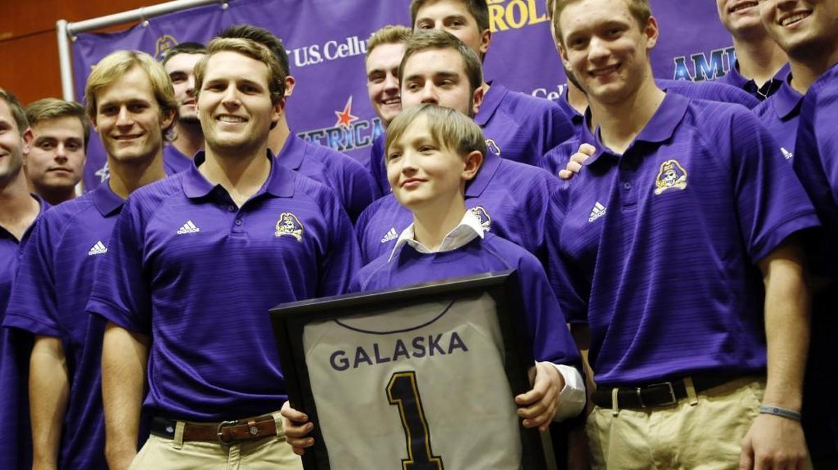 Rhettec Galaska, center, 11, who has battled non-Hodgkins lymphoma, poses for a photo with the ECU baseball team after he was presented a framed uniform with his name by ECU head baseball coach Cliff Godwin. Rhettec also signed a “letter of intent” to join the baseball team as an honorary member on Dec. 7.