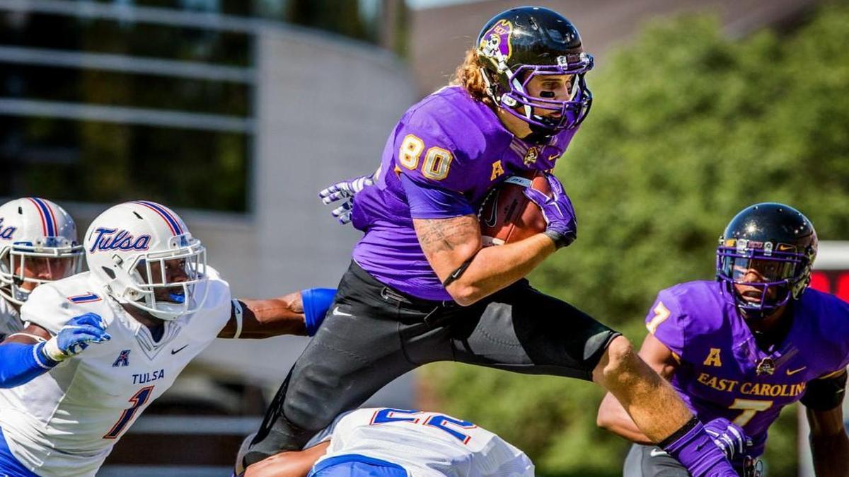 East Carolina's Bryce Williams jumps over Tulsa's Jeremy Brady during an NCAA college football game in Greenville.