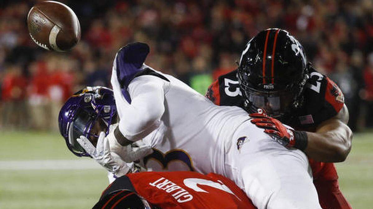 East Carolina running back Anthony Scott (3) loses the ball as he is tackled by Cincinnati linebacker Eric Wilson (23) and safety Tyrell Gilbert (2) during the first half of the game in Cincinnati.