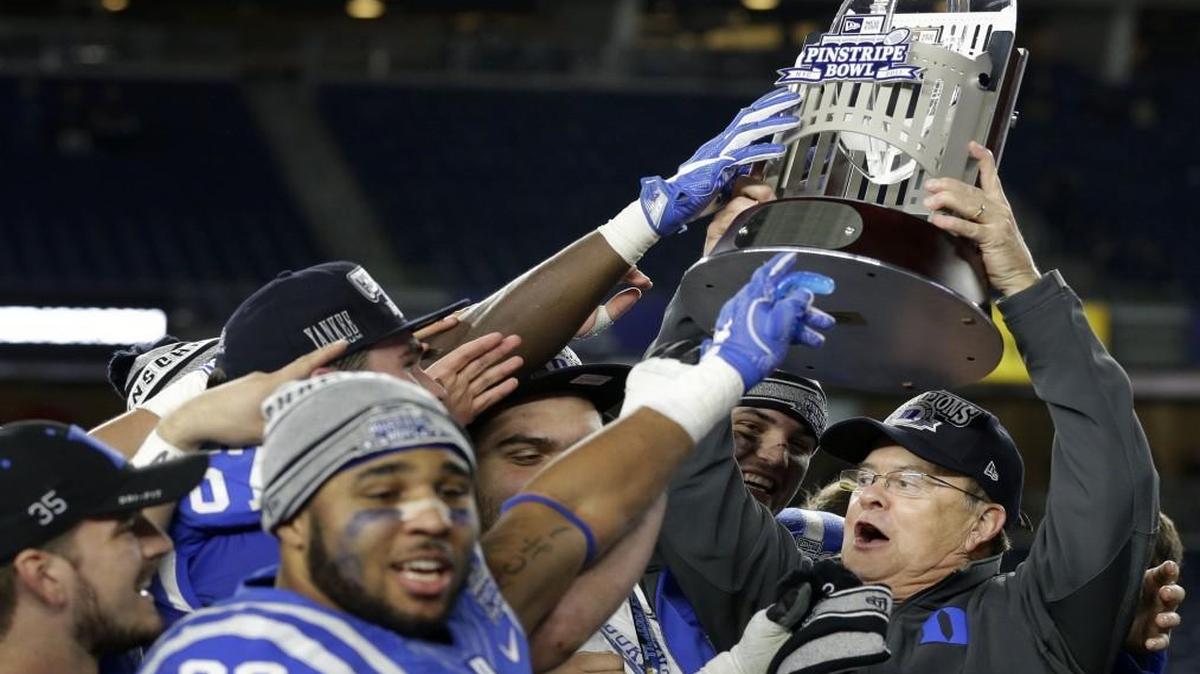 With Frank Sinatra’s version of “New York, New York” blaring of the PA, Duke coach David Cutcliffe, right, hoists the Pinstripe Bowl trophy after his Blue Devils defeated Indiana 44-41 in overtime at Yankee Stadium in New York. Cutcliffe said he was thinking “Lord, when do I die? Because I’m in heaven now.”