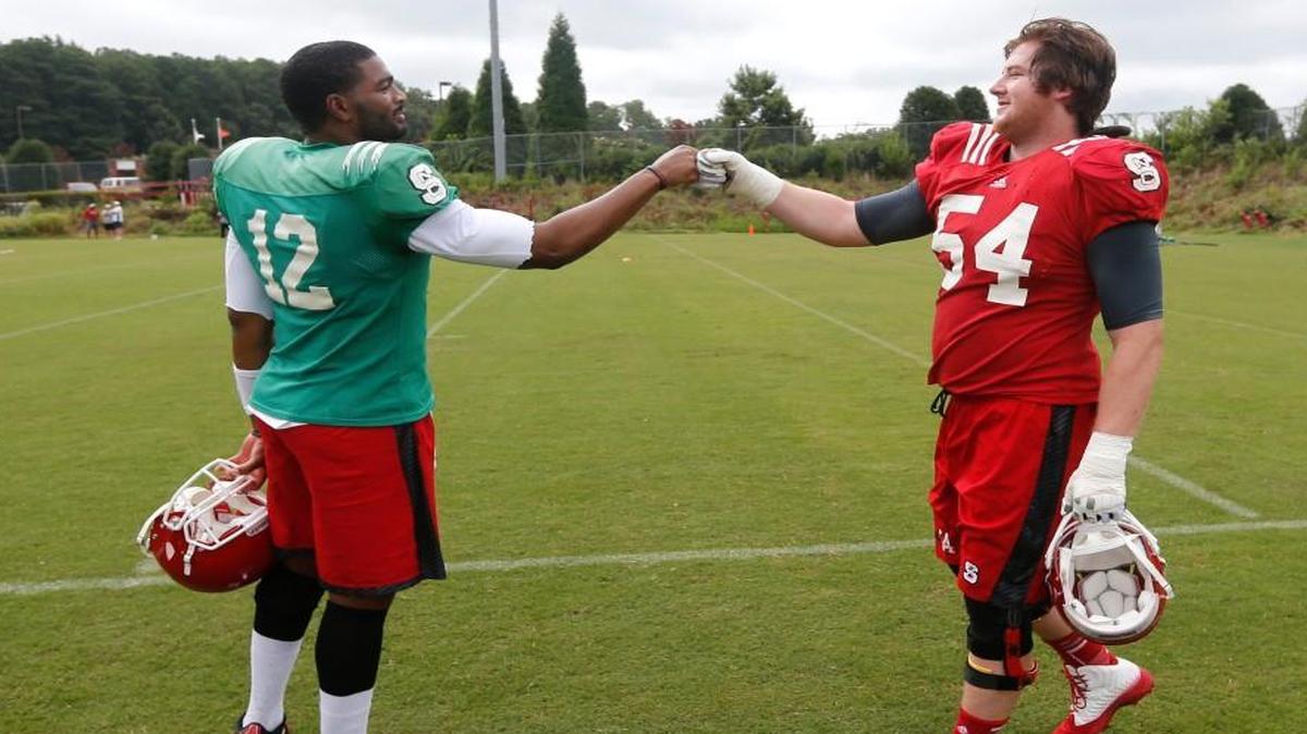 N.C. State quarterback Jacoby Brissett fist bumps guard Joe Thuney (54) during the Wolfpack's third football practice of the preseason Monday, August 4, 2014.