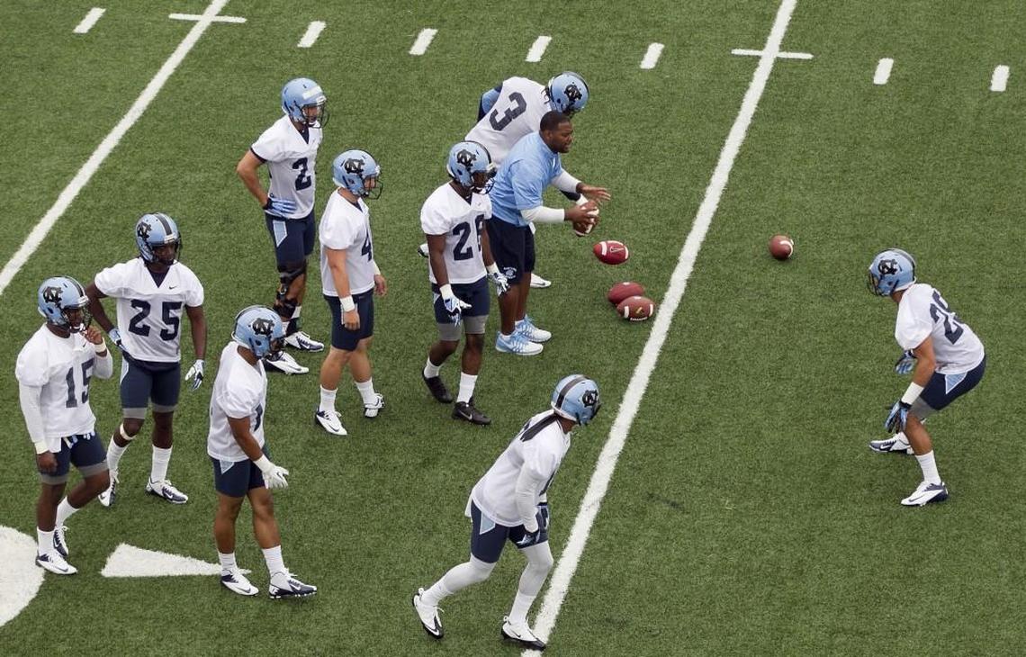 UNC defensive graduate assistant coach Cameron O’Neill works with players during the Tar Heels’ opening day of practice for the 2014 season. The issue of staff size remains a sore point at college programs, with concerns raised by less generously endowed programs.