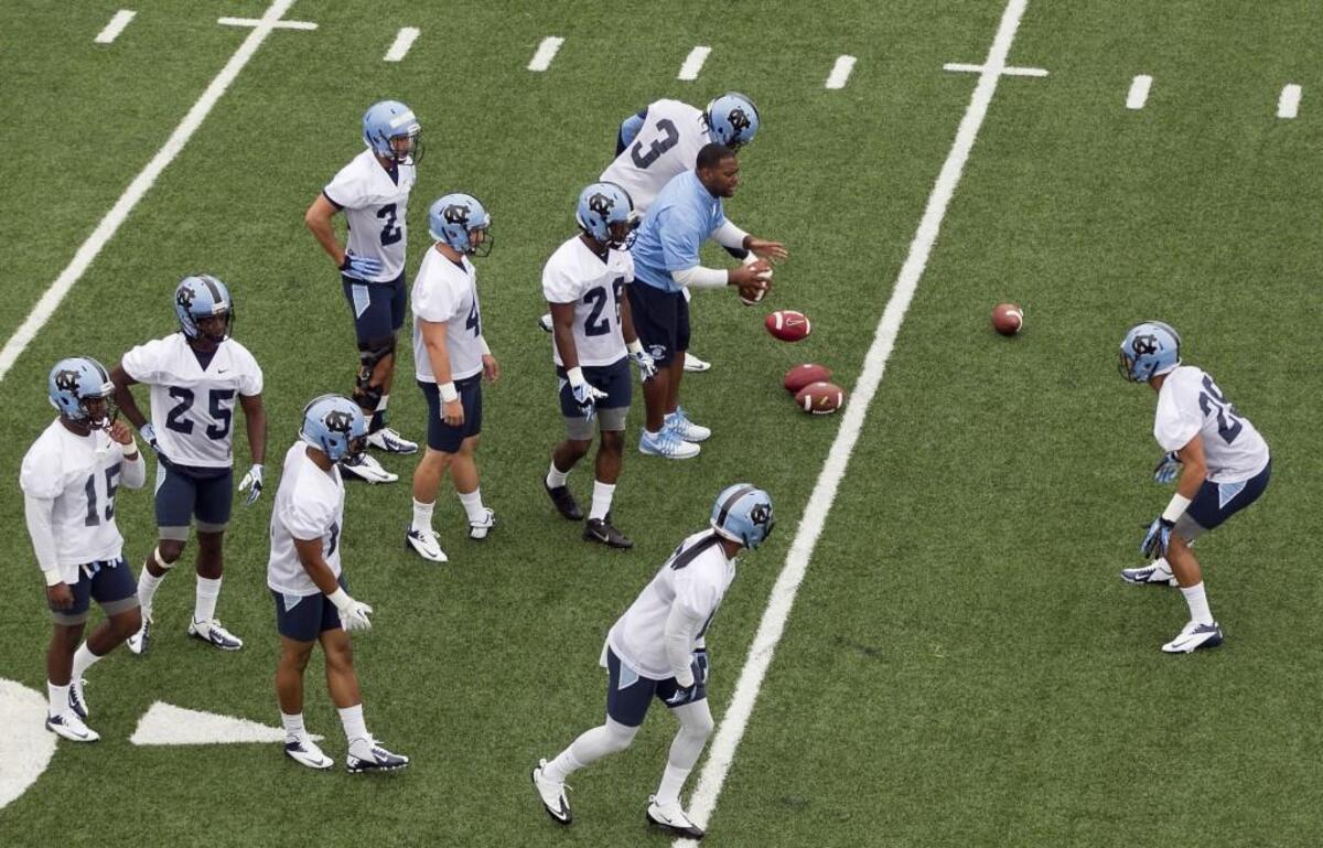 UNC defensive graduate assistant coach Cameron O’Neill works with players during the Tar Heels’ opening day of practice for the 2014 season. The issue of staff size remains a sore point at college programs, with concerns raised by less generously endowed programs.