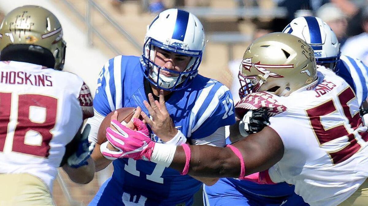 Duke quarterback Daniel Jones (17) runs by Florida State's Fredrick Jones (55) for yardage.