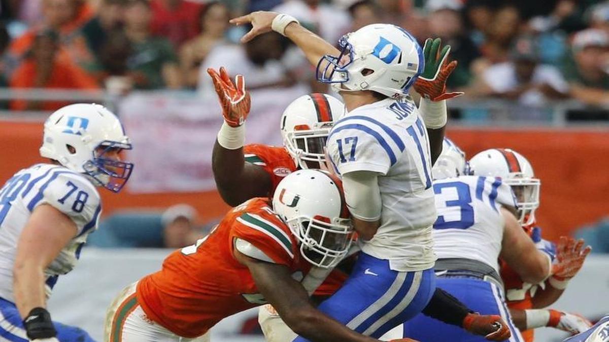 Miami defensive lineman Kendrick Norton (7) and defensive back Rayshawn Jenkins (26) hit Duke quarterback Daniel Jones (17) as he gets off the pass in the second quarter .