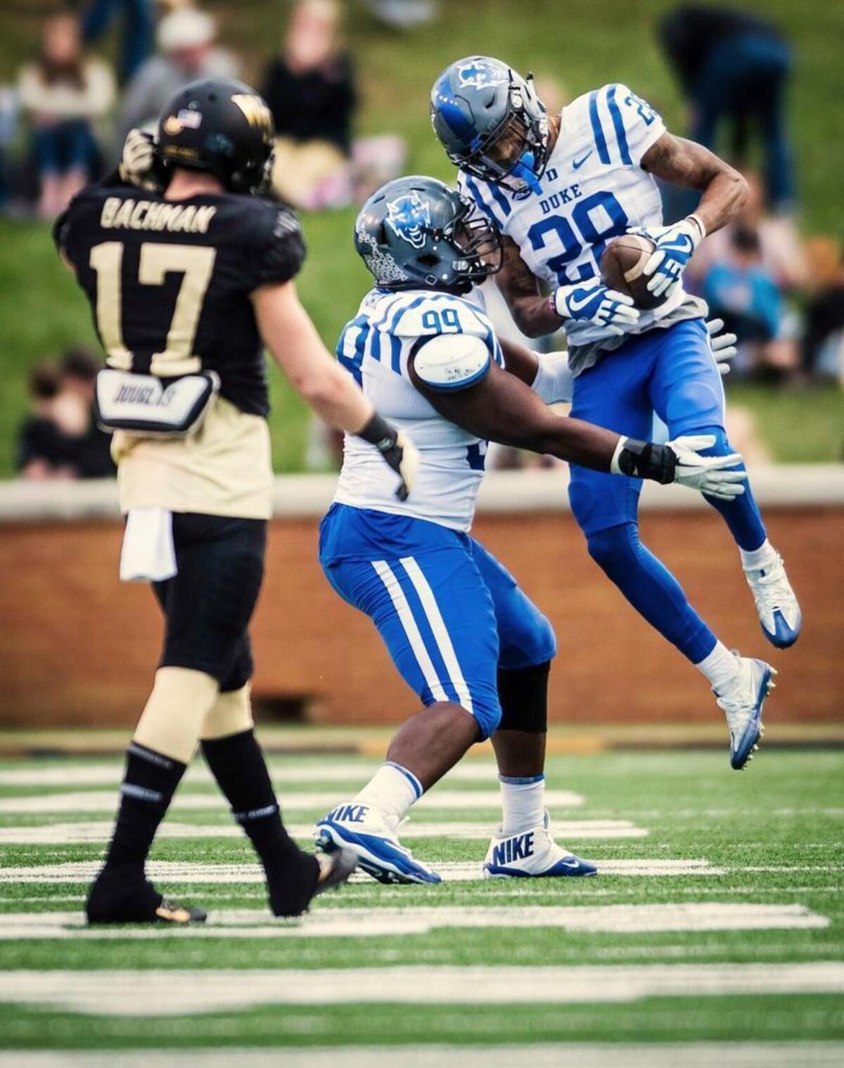 Duke cornerback Mark Gilbert (28) and defensive tackle Mike Ramsey (99) celebrate Gilbert's interception against Wake Forest wide receiver Alex Backmann (17) on Nov. 25, 2017, in Winston-Salem. (Allison Lee Isley/The Winston-Salem Journal via AP)