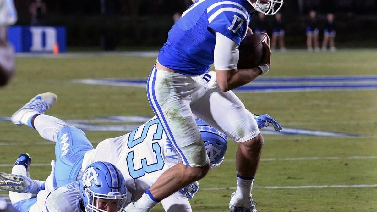 Duke quarterback Daniel Jones, right, breaks away from North Carolina defensive end Malik Carney (53) and linebacker Cole Holcomb (36) in November.