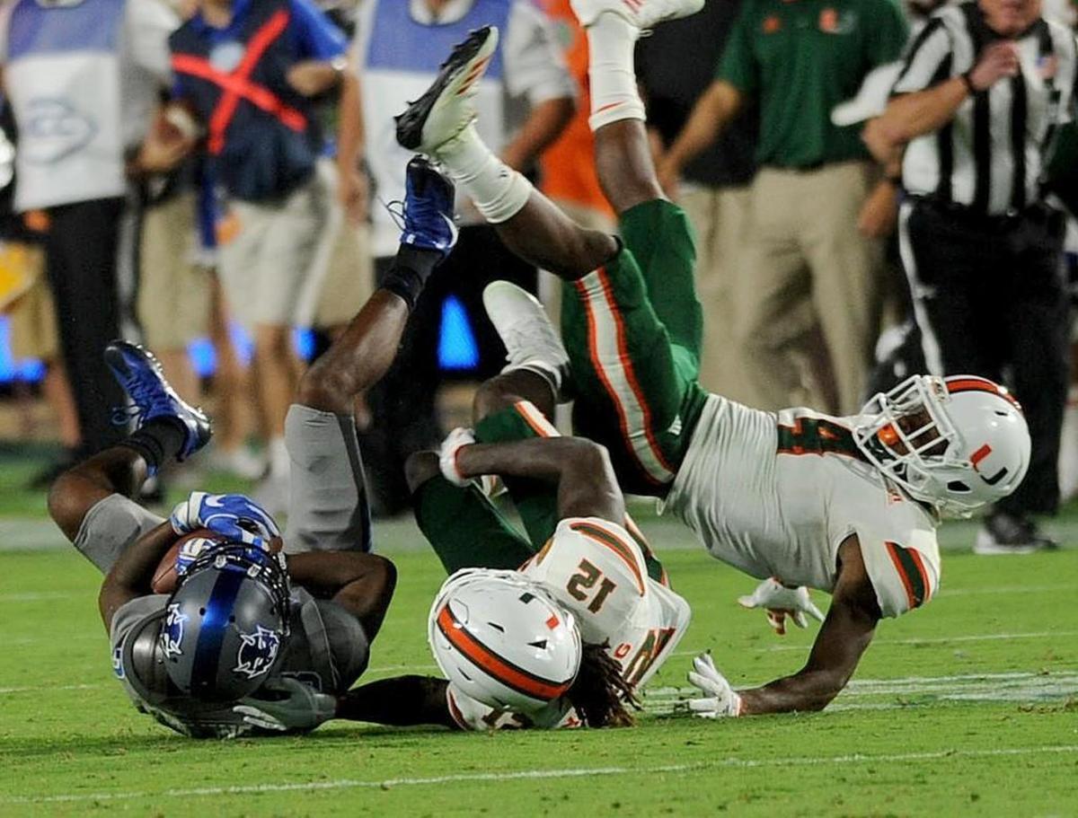 Duke's Johnathan Lloyd (5) battles Miami's Malek Young (12) and Jaquan Johnson (4) for a first down Friday in Wallace Wade Stadium.