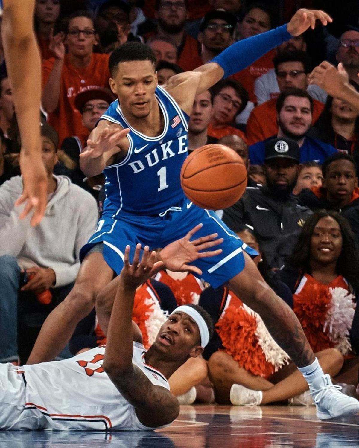St. John's Tariq Owens, bottom, passes the ball as Duke's Trevon Duval (1) defends during the first half.