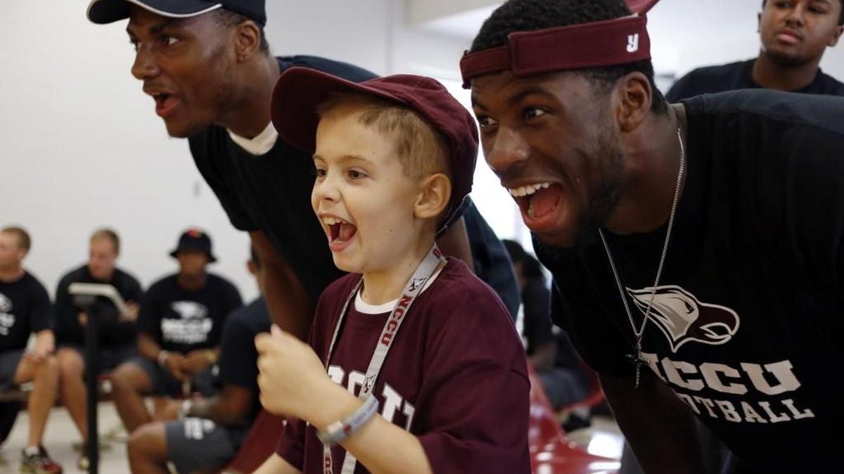 Howell Brown III, 10, screams along with NC Central football players C.J. Moore, left, and Tre Smith as they watch another player nearly get a strike while bowling in 2014.