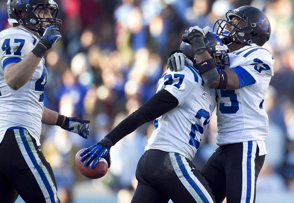 Duke’s Devon Edwards, middle, is embraced by teammate Deondre Singleton, right, after Edwards intercepted a pass by North Carolina’s Marquise Williams with less than two minutes to play in the fourth quarter, securing a 27-25 victory over UNC in 2013.