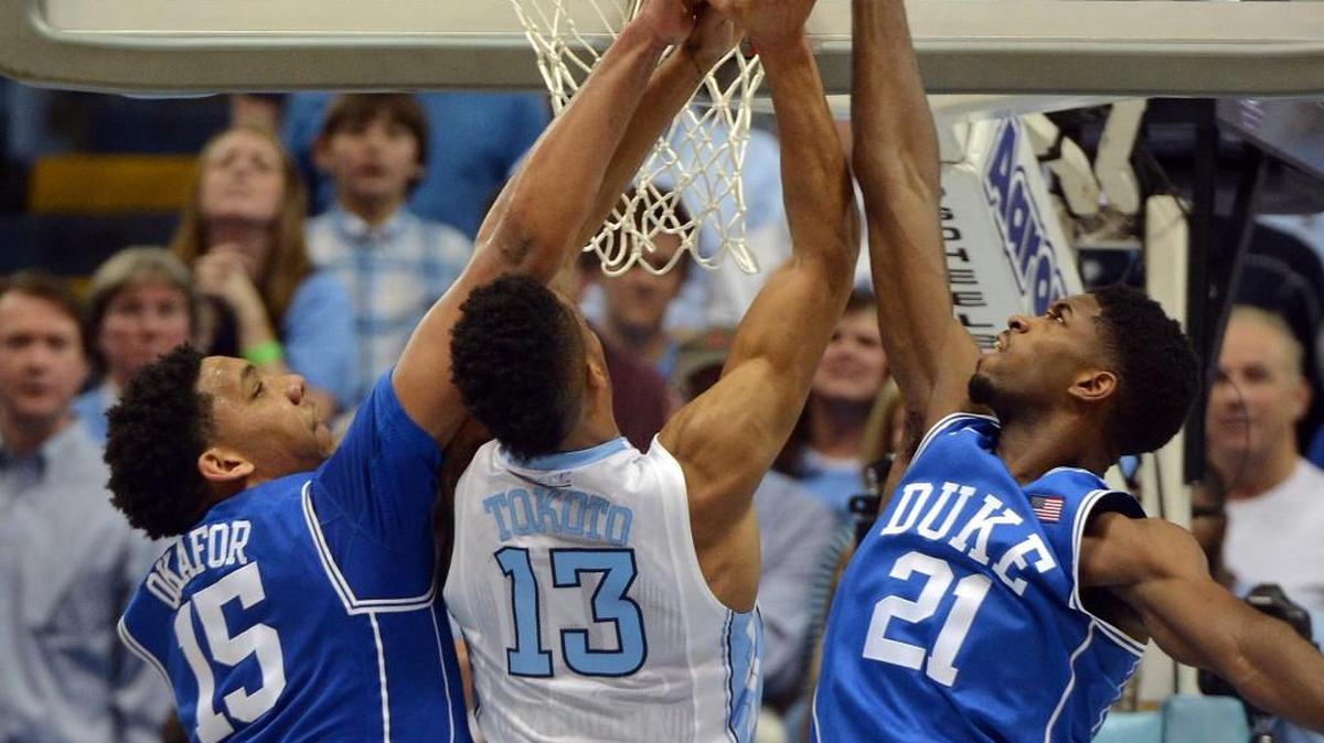 Duke center Jahlil Okafor, left, and forward Amile Jefferson, right, block a shot by UNC forward J.P. Tokoto, middle, on March 7, 2015.