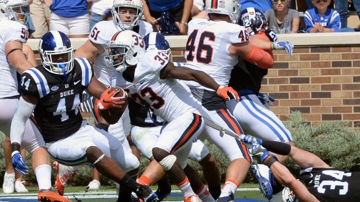 Duke's Ben Humphreys (34) holds onto Virginia's Olamide Zaccheaus (33) jersey to prevent a two point conversion attempt in the first half at Wallace Wade Stadium Saturday.