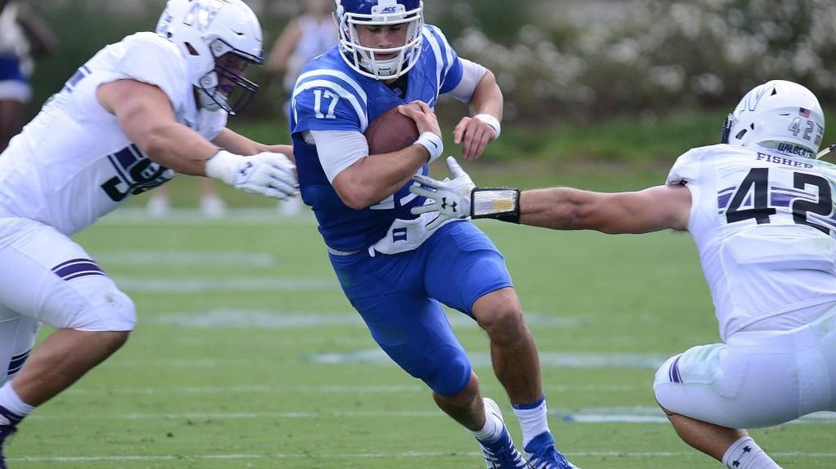 Duke quarterback Daniel Jones runs between Northwestern’s Paddy Fisher, right, and Tommy Camifax, left.