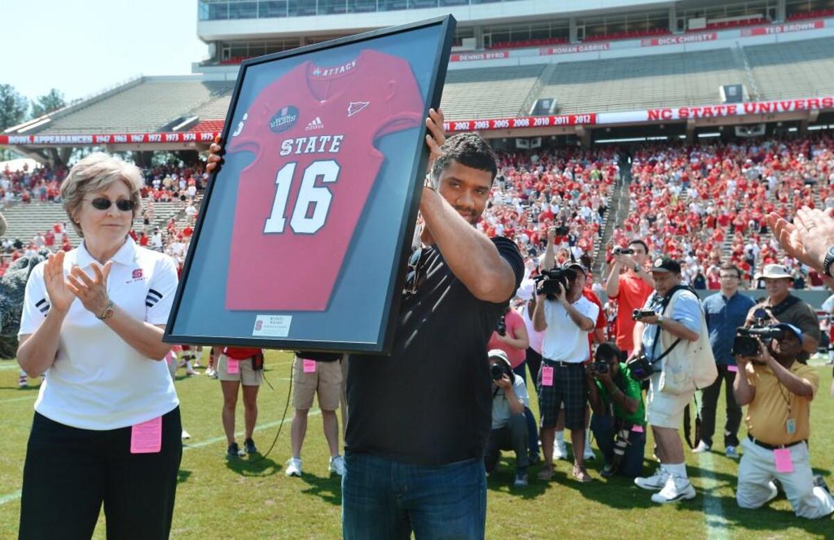 Former N.C. State quarterback and Super Bowl XLVIII champ Russell Wilson holds up his framed No. 16 Wolfpack jersey as he was honored on April 12, 2014.