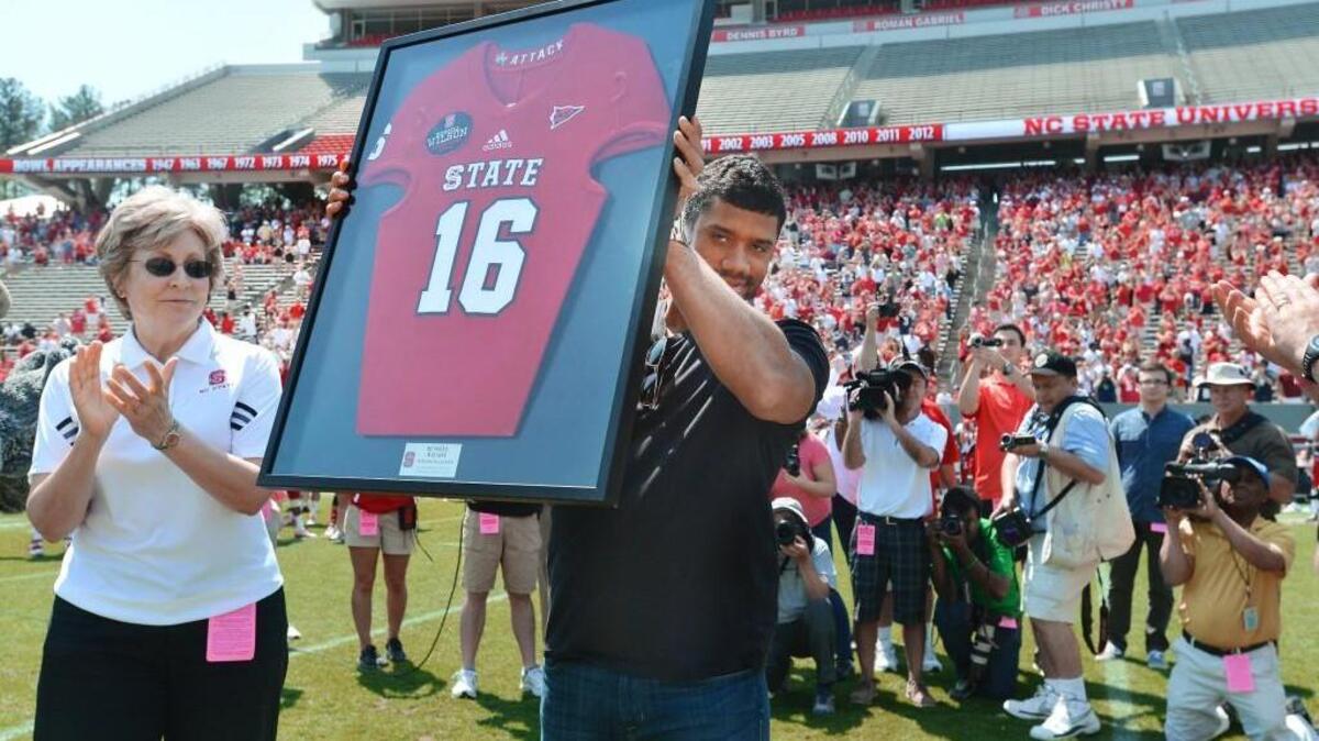 Former N.C. State quarterback and Super Bowl XLVIII champ Russell Wilson holds up his framed No. 16 Wolfpack jersey as he was honored on April 12, 2014.