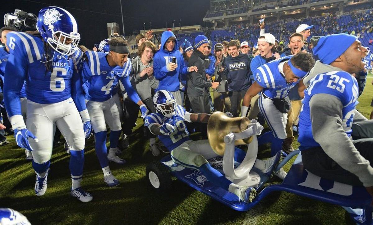 The Duke football team celebrates with the Victory Bell after beating North Carolina in November 2016.