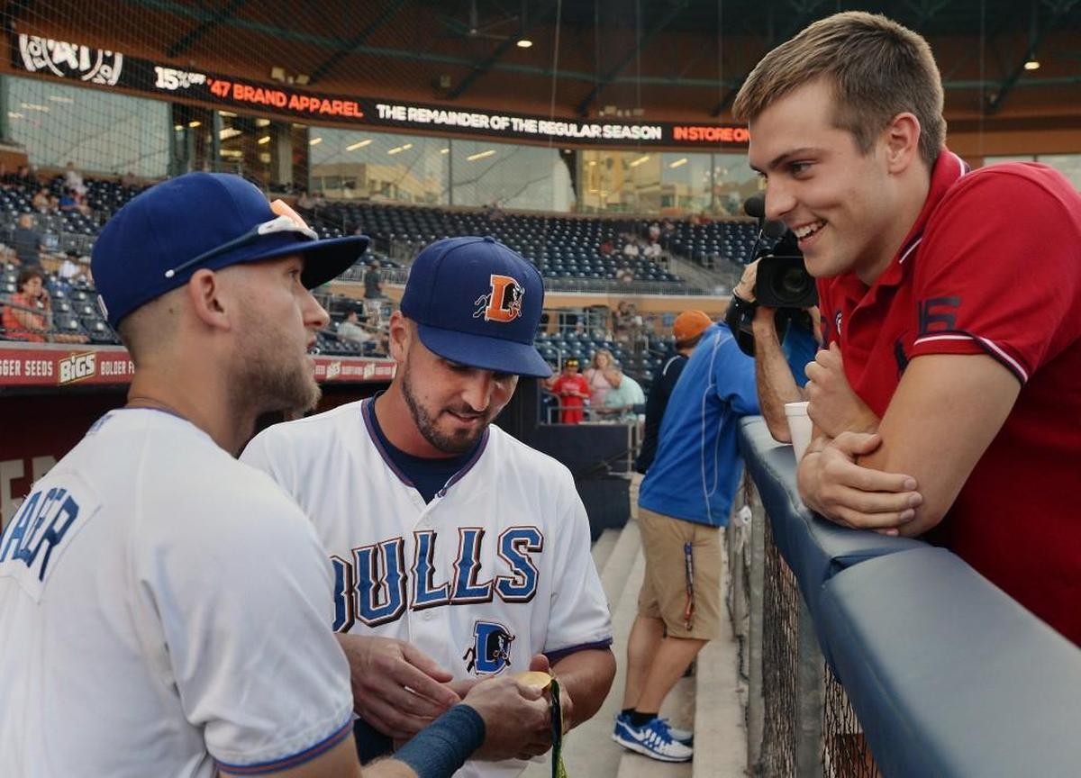 Olympic gold medalist Ryan Held, right, lets Durham Bulls players Jake Goebbert, middle, and Jake Hager, left, check out his gold medal before throwing out the first pitch on Aug. 30, 2016.