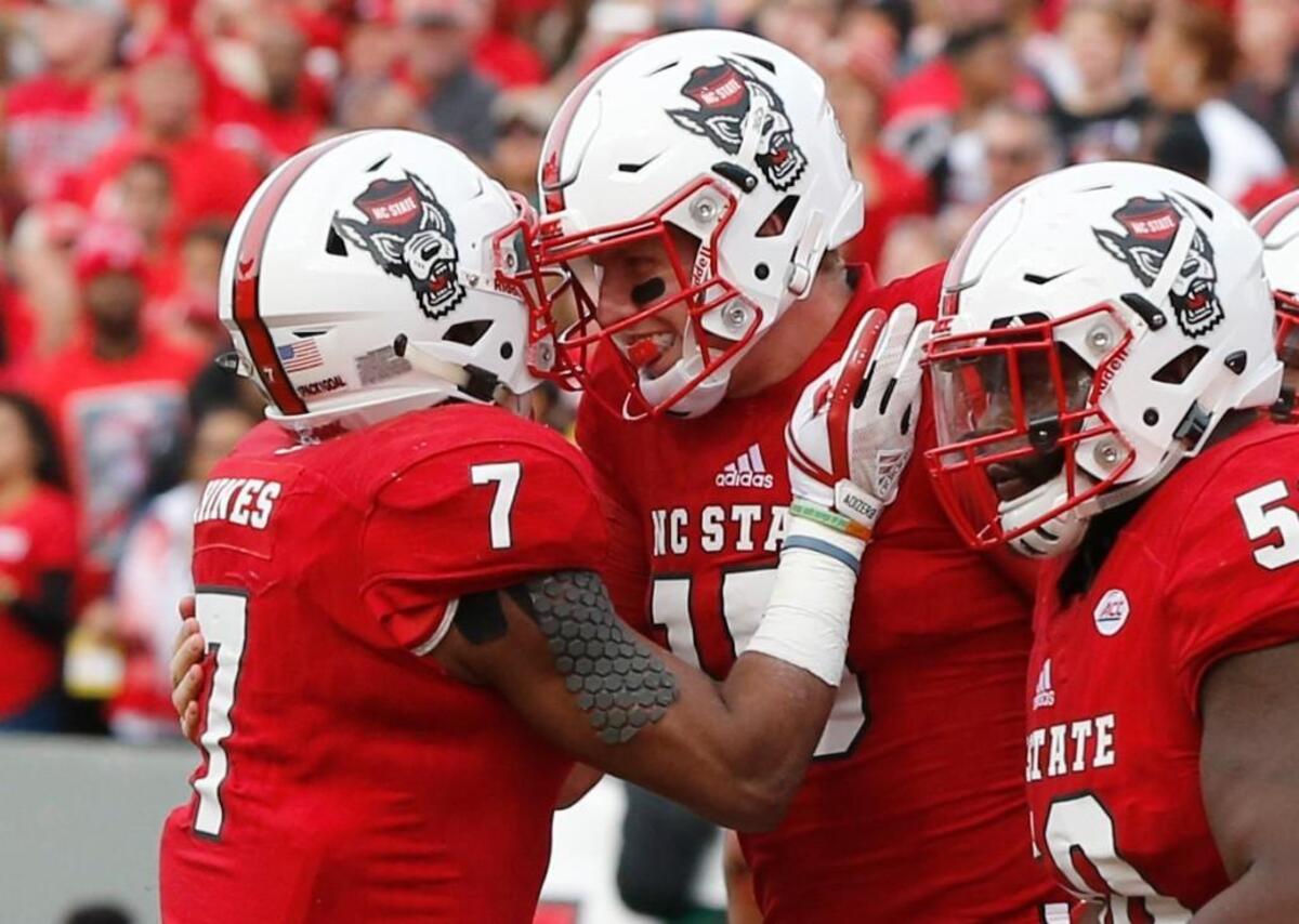 N.C. State quarterback Ryan Finley, middle, celebrates with Nyheim Hines, left, after scoring on a 3-yard run against UNC on Nov. 25.