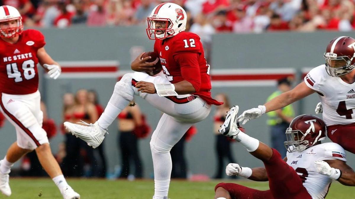 N.C. State’s Jacoby Brissett (12) escapes from Troy linebacker William Lloyd during the Wolfpack's game against Troy at Carter-Finley Stadium in Raleigh, Saturday, Sept. 5, 2015.