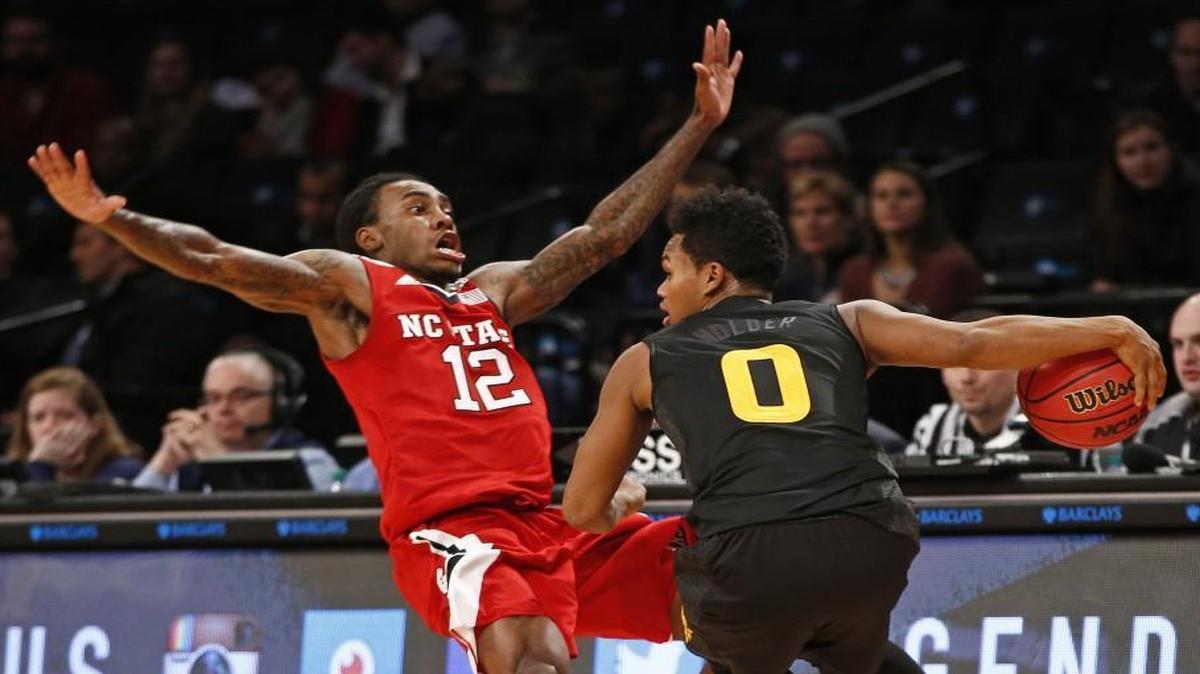 N.C. State guard Anthony Barber (12) tries to avoid drawing a foul as Arizona State guard Tra Holder (0) drives down court in the second half of a Legends Classic semifinal in New York.