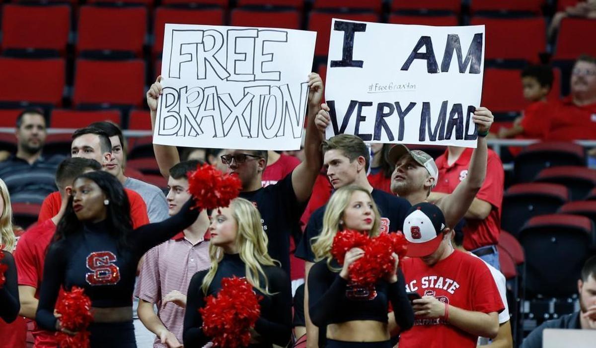 Fans hold up signs supporting Braxton Beverly during N.C. State's exhibition game against Mars Hill University at PNC Arena Friday, Nov. 3, 2017.