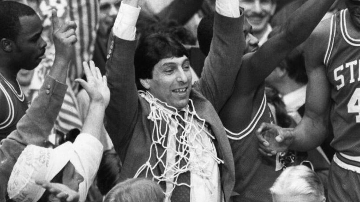 North Carolina State coach Jim Valvano lifts up National Championship trophy moments after Lorenzo Charles had dunked a shot to give North Carolina State the win over Houston April 5, 1983 in the NCAA final at Albuquerque. (News & Observer File Photo)