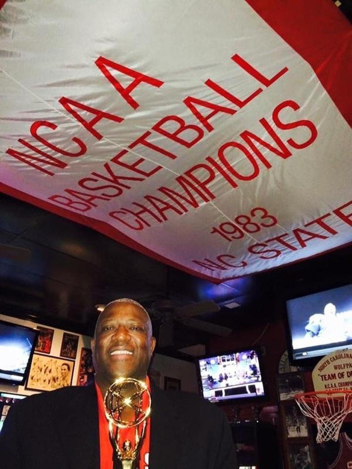 Dereck Whittenburg, of the NC State stars of 1983, stands underneath a championship banner at Amedeo’s as he displayed the Emmy won from ESPN’s 30 for 30 documentary “Survive and Advance.”