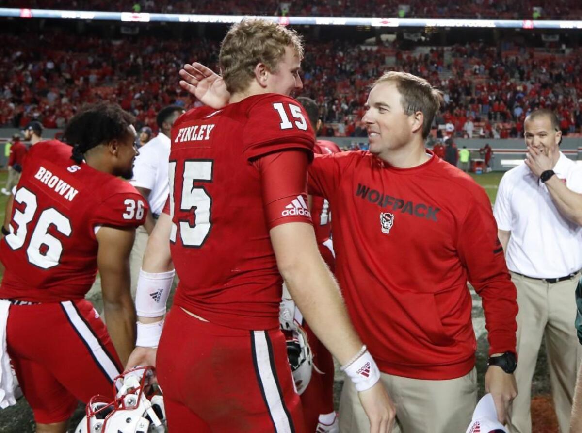 N.C. State offensive coordinator Eliah Drinkwitz, right, celebrates with quarterback Ryan Finley after N.C. State’s 33-21 win over UNC in November.
