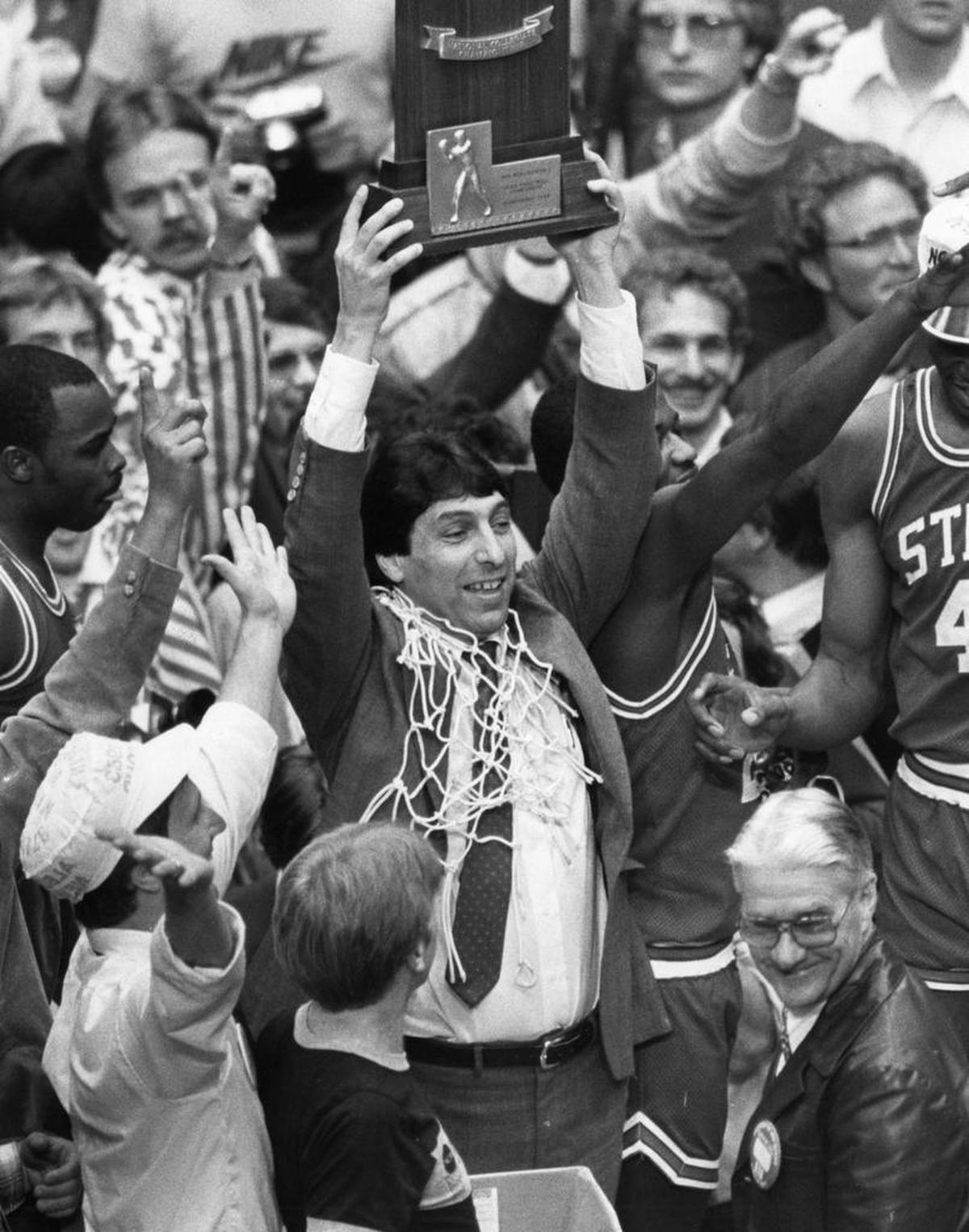 N.C. State coach Jim Valvano lifts up the National Championship trophy moments after Lorenzo Charles dunked a shot to give the Wolfpack the win over Houston on April 5, 1983 in the NCAA final at Albuquerque. (News & Observer File Photo)