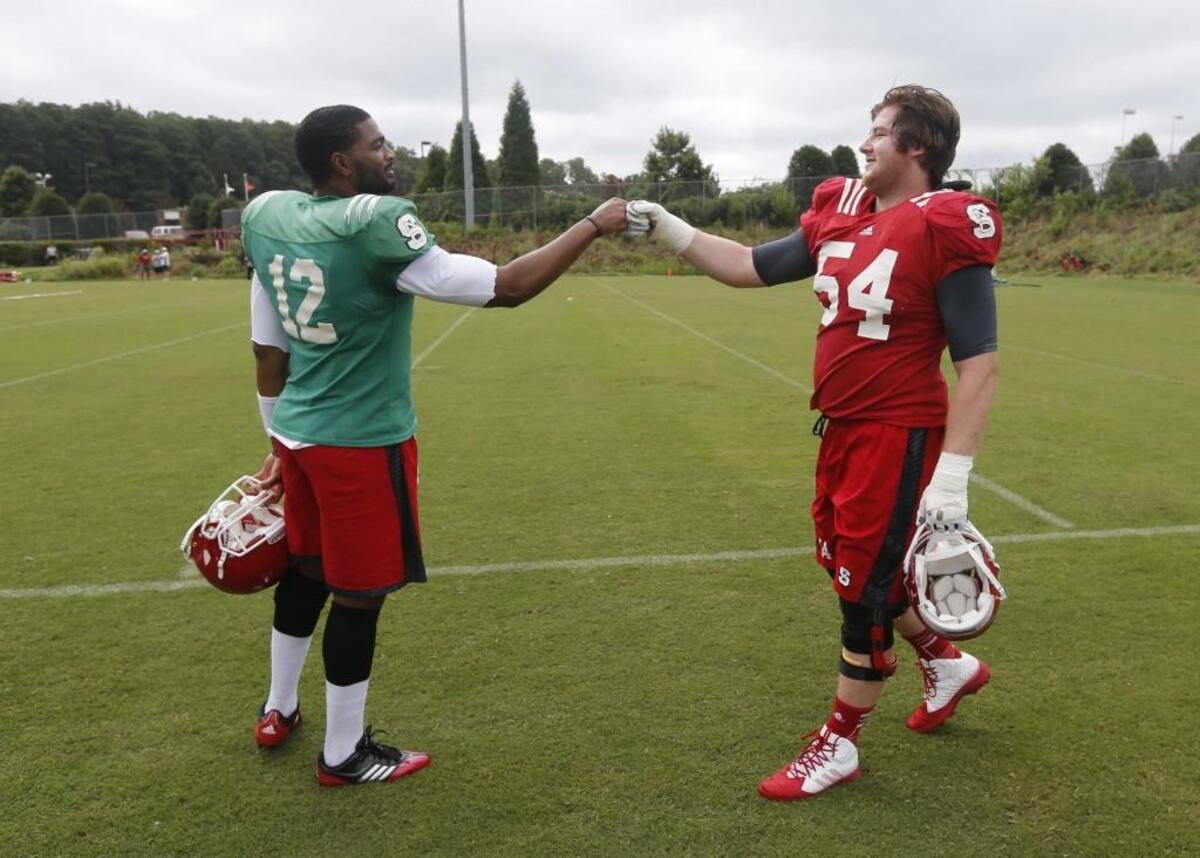 N.C. State quarterback Jacoby Brissett fist bumps guard Joe Thuney (54) during the Wolfpack’s third football practice of the preseason on Aug. 4, 2014, at N.C. State’s practice fields. The two were teammates on the New England Patriots team that won Super Bowl LI.