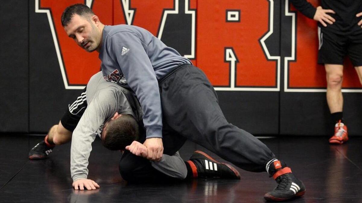 Head wrestling coach Pat Popolizio demonstrate a maneuver with wrestler Nicky Hall during wrestling practice in the Weisiger-Brown Athletics Facility in Raleigh Thursday, Dec. 9, 2015. The Wolfpack wrestling team is ranked number five in the country.
