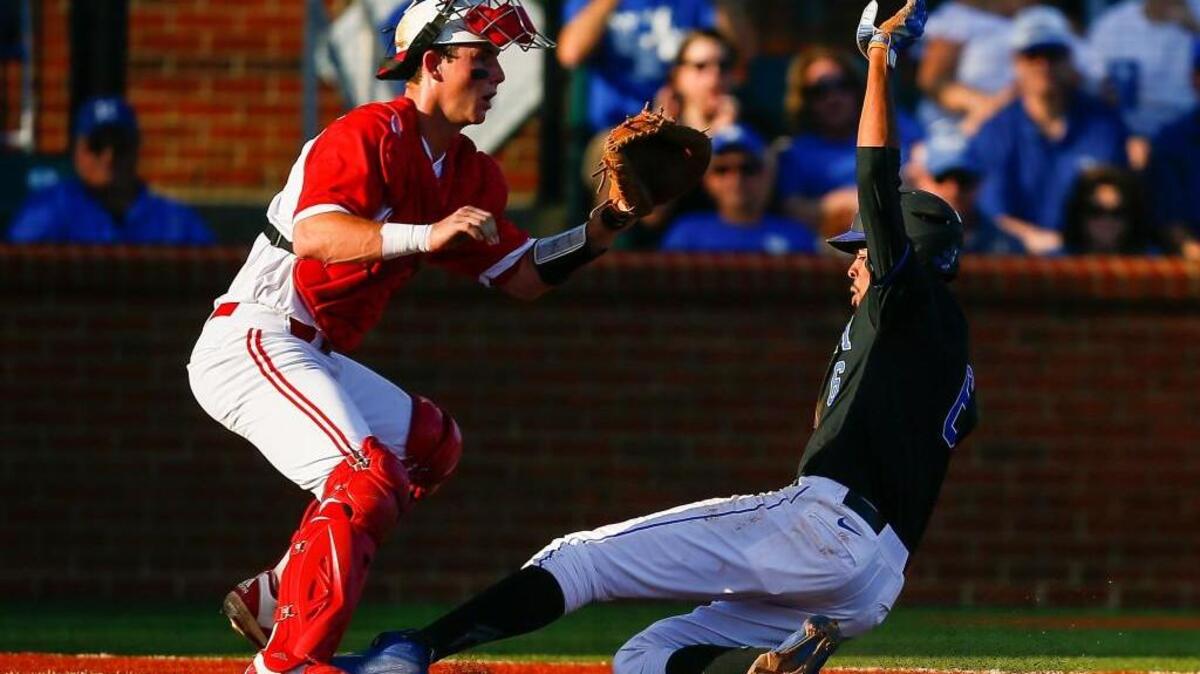 Kentucky’s Tristan Pompey, right, scores against N.C. State catcher Andy Cosgrove on Saturday. The Wolfpack and Wildcats play again Monday for a trip to the NCAA baseball super regionals.