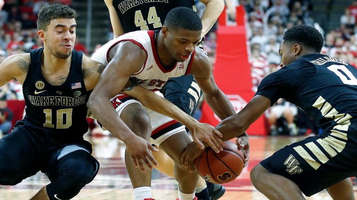 Wake Forest's Mitchell Wilbekin, left, and Brandon Childress go after the ball with N.C. State's Dennis Smith Jr. during the second half at PNC Arena.